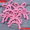 Ten pink embroidered cartoon bow iron-on patches scattered on a denim fabric.