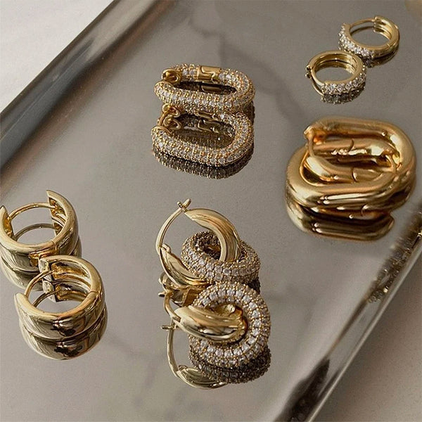 Collection de boucles d'oreilles créoles dorées, présentées sur un plateau argenté.