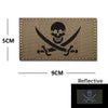A brown embroidered patch featuring a skull and crossed swords design with reflective accents.