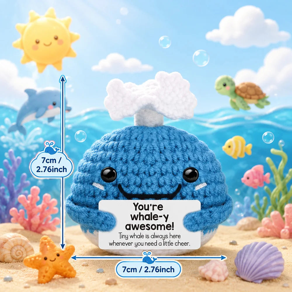 A blue crochet whale plush toy surrounded by sea creatures and seashells.
