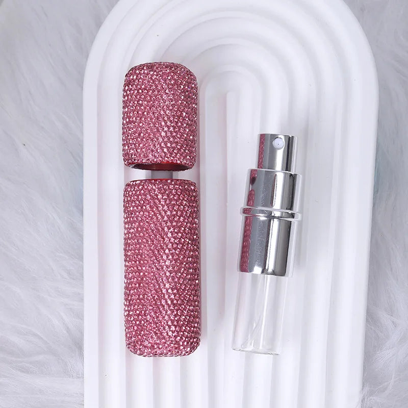 A pink textured glass perfume atomizer refill with a silver cap displayed in a white holder.