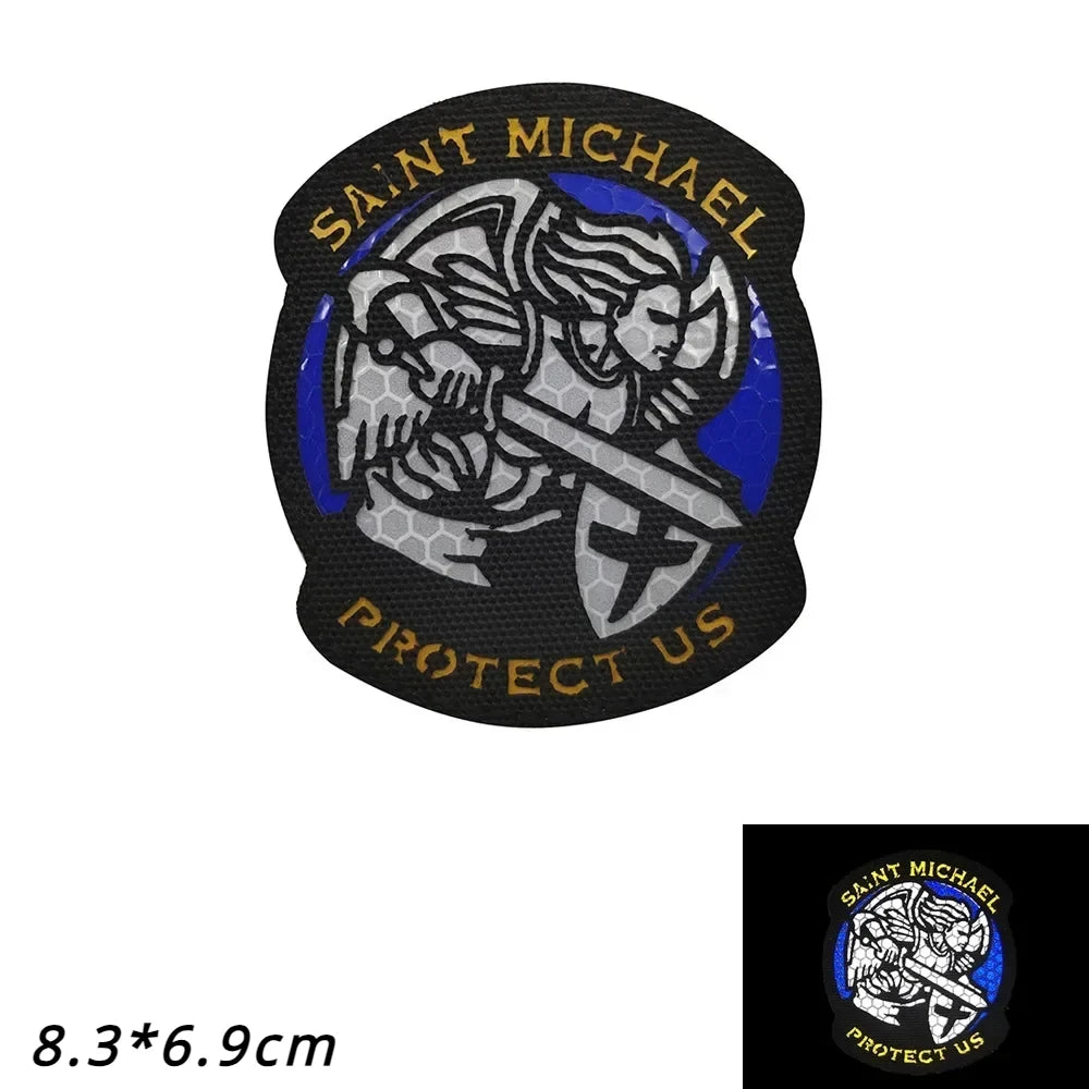 A black patch featuring the text SAINT MICHAEL PROTECT US surrounding an archangel figure.
