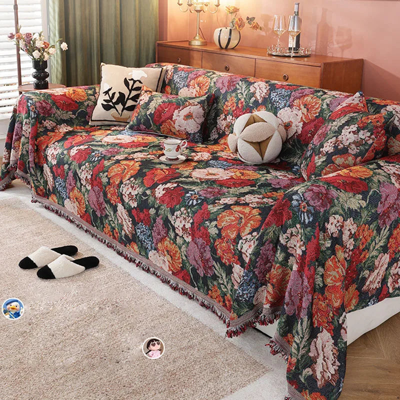 A romantic floral jacquard sofa blanket featuring rich colors and tassels draped over a sofa.