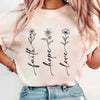 A light pink t-shirt featuring black line art designs of faith, hope, and love.