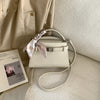 Beige eleganter PU-Leder-Clutchtasche mit geflochtenem Riemchen auf hellem Stoff.