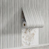 Roll of wood grain peel-and-stick wall tiles in light gray and white stripes mounted on a white wall.
