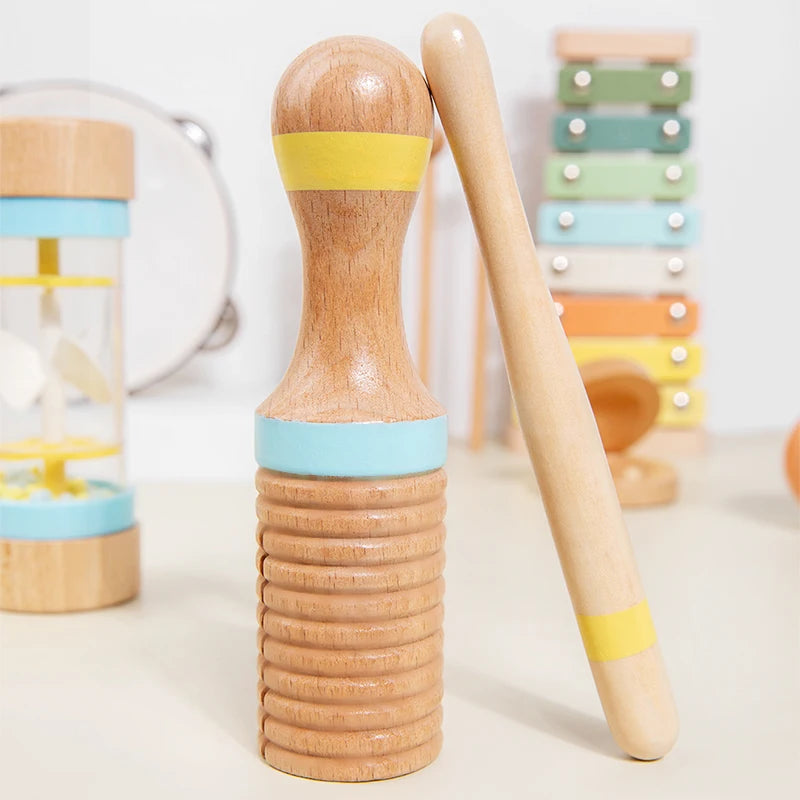 A wooden percussion instrument set for kids showing a mallet and a cylindrical drum with colored bands.
