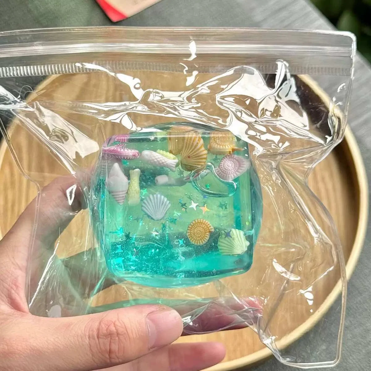 A clear plastic bag contains several teal-colored ocean squishy stress balls with various shell shapes.
