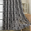 A black and white tree bark jacquard blackout curtain panel hanging in a light-colored room.