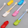 A collection of colorful adhesive wall-mounted toothbrush holders with drainage holes in yellow, blue, pink, and green.