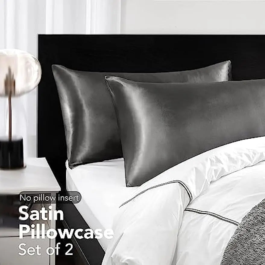 Un juego de dos fundas de almohada de satén color coral sobre una cama blanca con ropa de cama blanca.