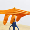 A bright orange heavy-duty nitrile disposable glove with a diamond texture is displayed on a wooden surface.
