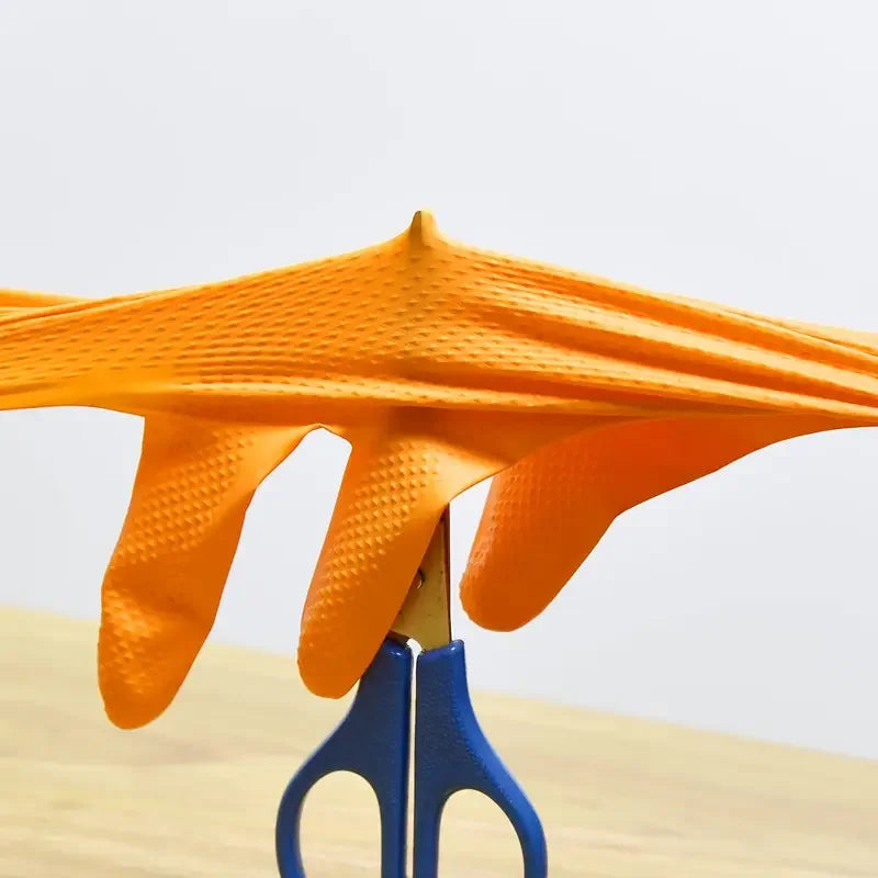 A bright orange heavy-duty nitrile disposable glove with a diamond texture is displayed on a wooden surface.