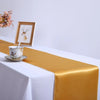 Elegant satin gold table runner on a white tablecloth with a framed picture and teacup.
