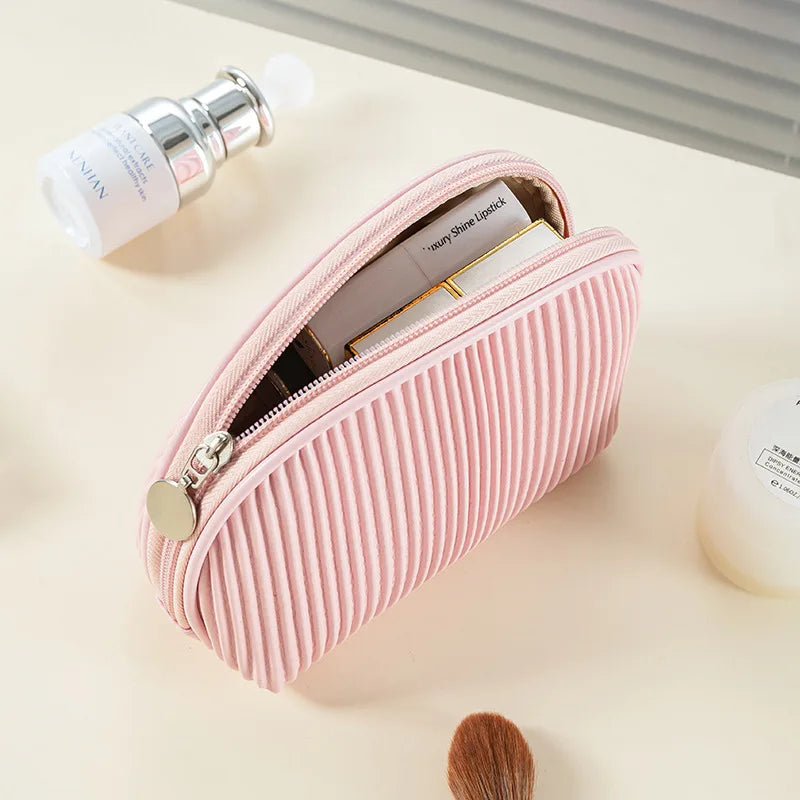 A pink ribbed PU leather makeup bag set with a zipper and a small white product tube is shown on a light surface.