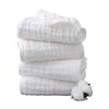 A stack of three white extra soft muslin burp cloths with a small white animal attached.