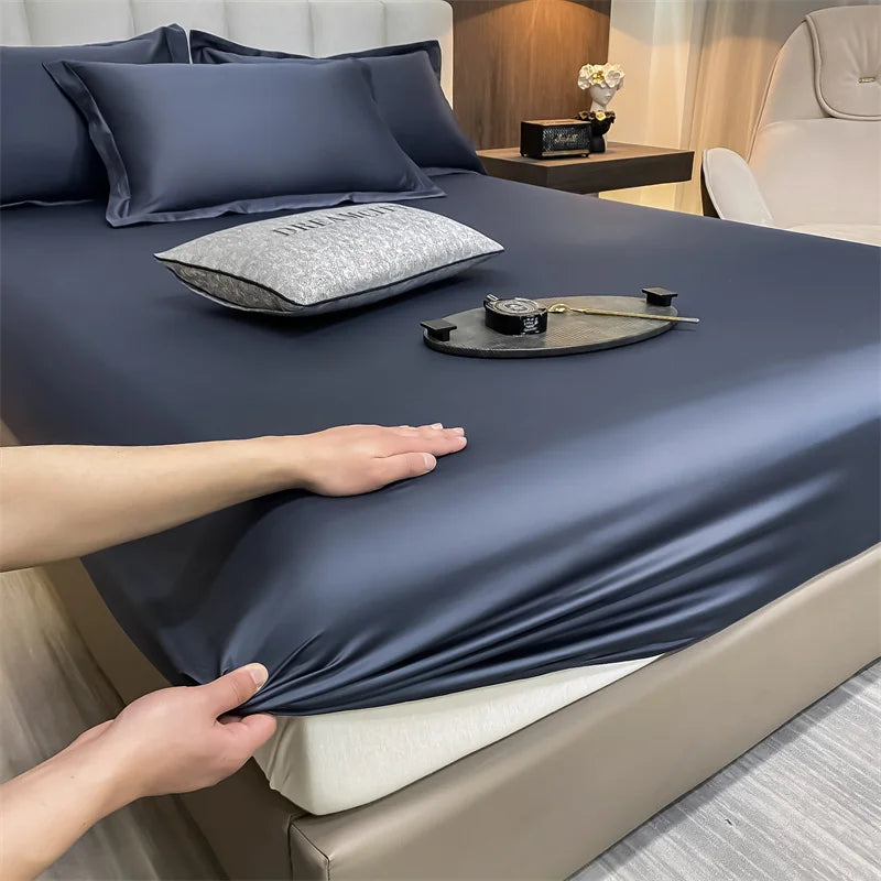 Una mano está ajustando un juego de sábanas de algodón liso y de lujo azul oscuro sobre una cama.