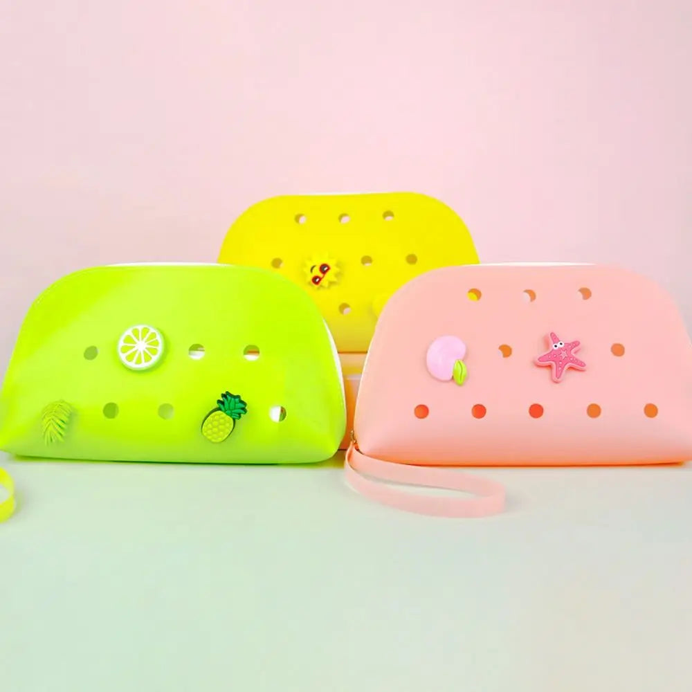 Drei Silikon-Münzbeutel in Gelb, Limettengrün und Pink mit Früchte- und Sternen-Dekorationen.