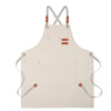 A light beige professional chef apron with cross-back straps and tool pockets.