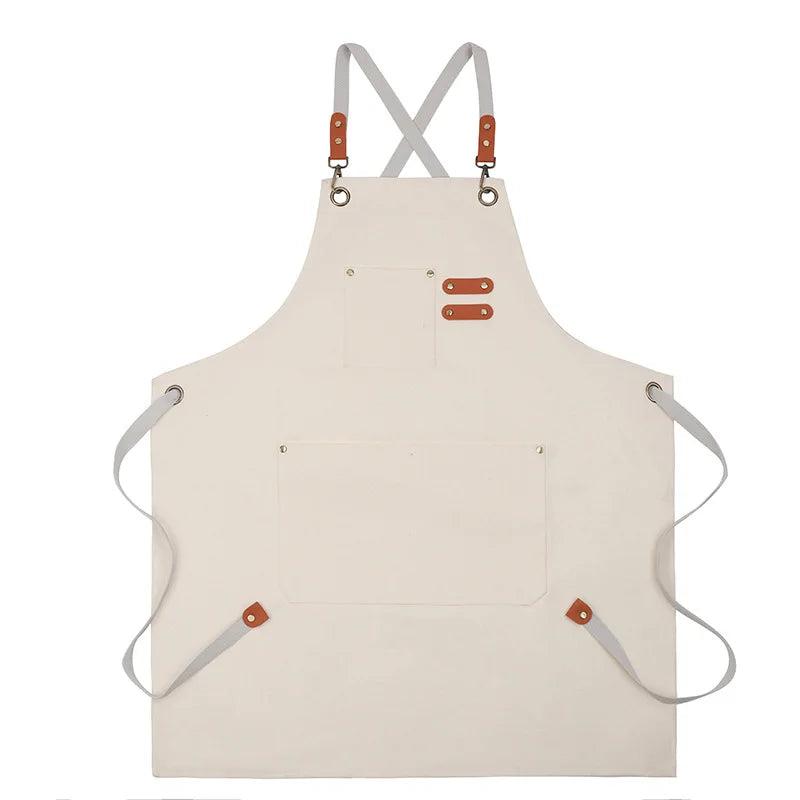 A light beige professional chef apron with cross-back straps and tool pockets.