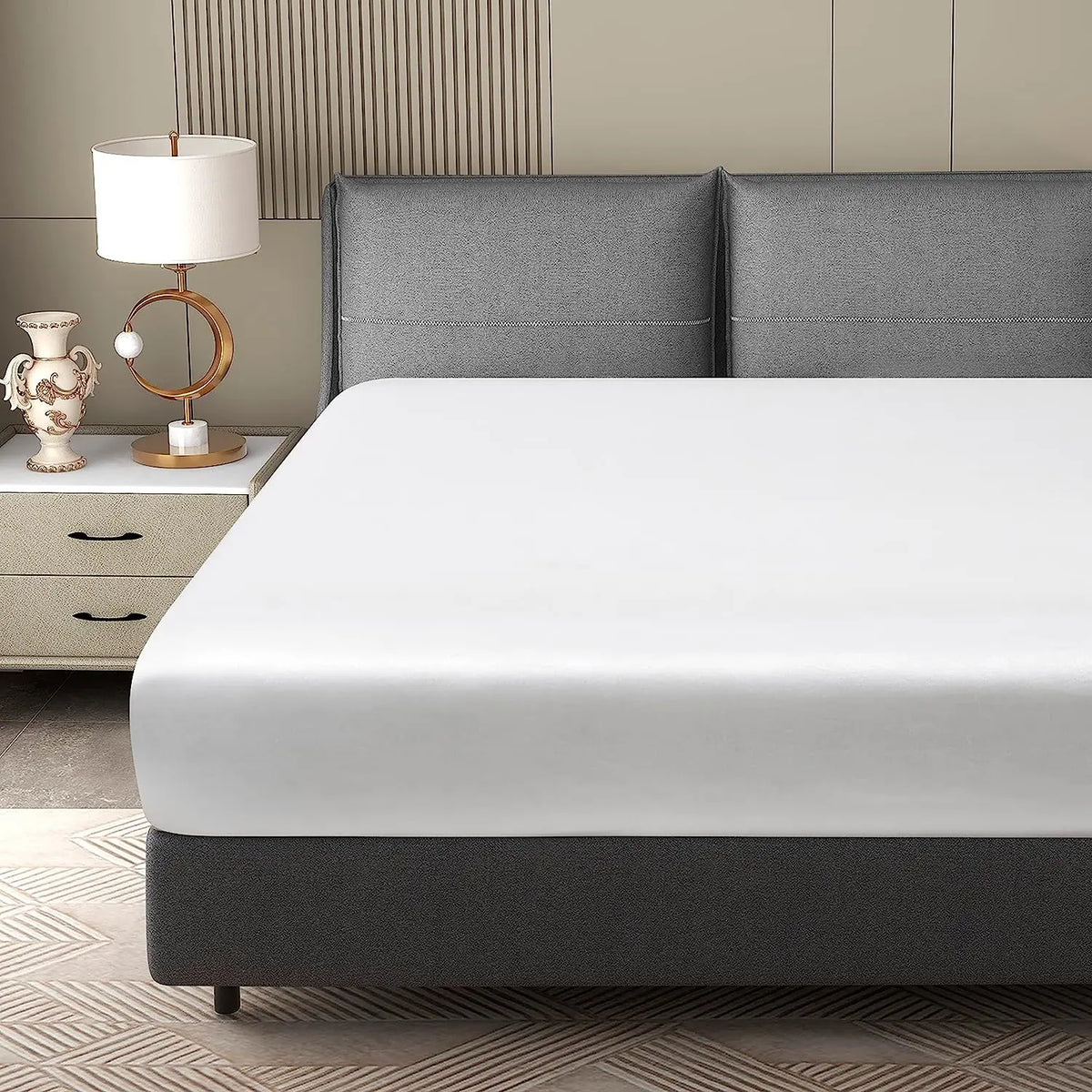 A modern bedroom featuring a bed with gray headboards and white bedding, next to a bedside table and lamp.
