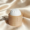 A beige silicone fidget keychain featuring a white, dome-shaped cake design.