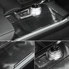 Close-up view of a car interior panel showing a carbon fiber vinyl wrap film and an electronic control knob.