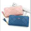 A pink quilted PU leather wristlet clutch wallet with a gold chain and tassels resting on a sheet of paper.