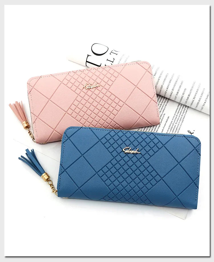 A pink quilted PU leather wristlet clutch wallet with a gold chain and tassels resting on a sheet of paper.