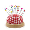 A collection of colorful round pearl straight pins arranged on a red and white checkered fabric base.