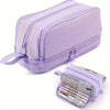 A lavender fabric pencil case with multiple zippered compartments and a strap is shown.
