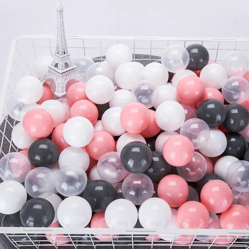 A white and pink ball pit filled with various sized clear, white, and pink plastic balls for toddlers.