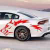 A white sports car features red flame decals on the rear fender and side, parked outdoors.