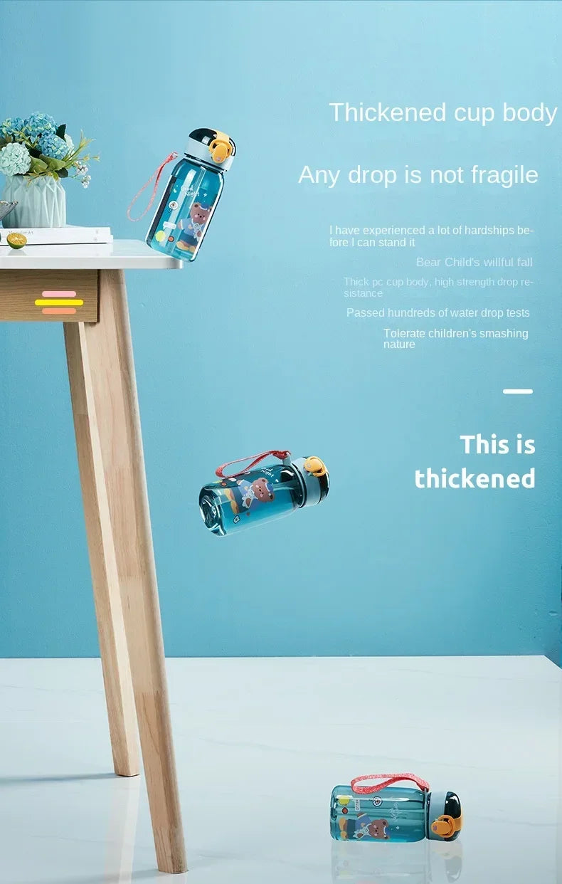 A blue cartoon straw water bottle is displayed on a wooden table against a light blue background.