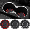 Two black silicone coasters with red accents shown in a car cup holder