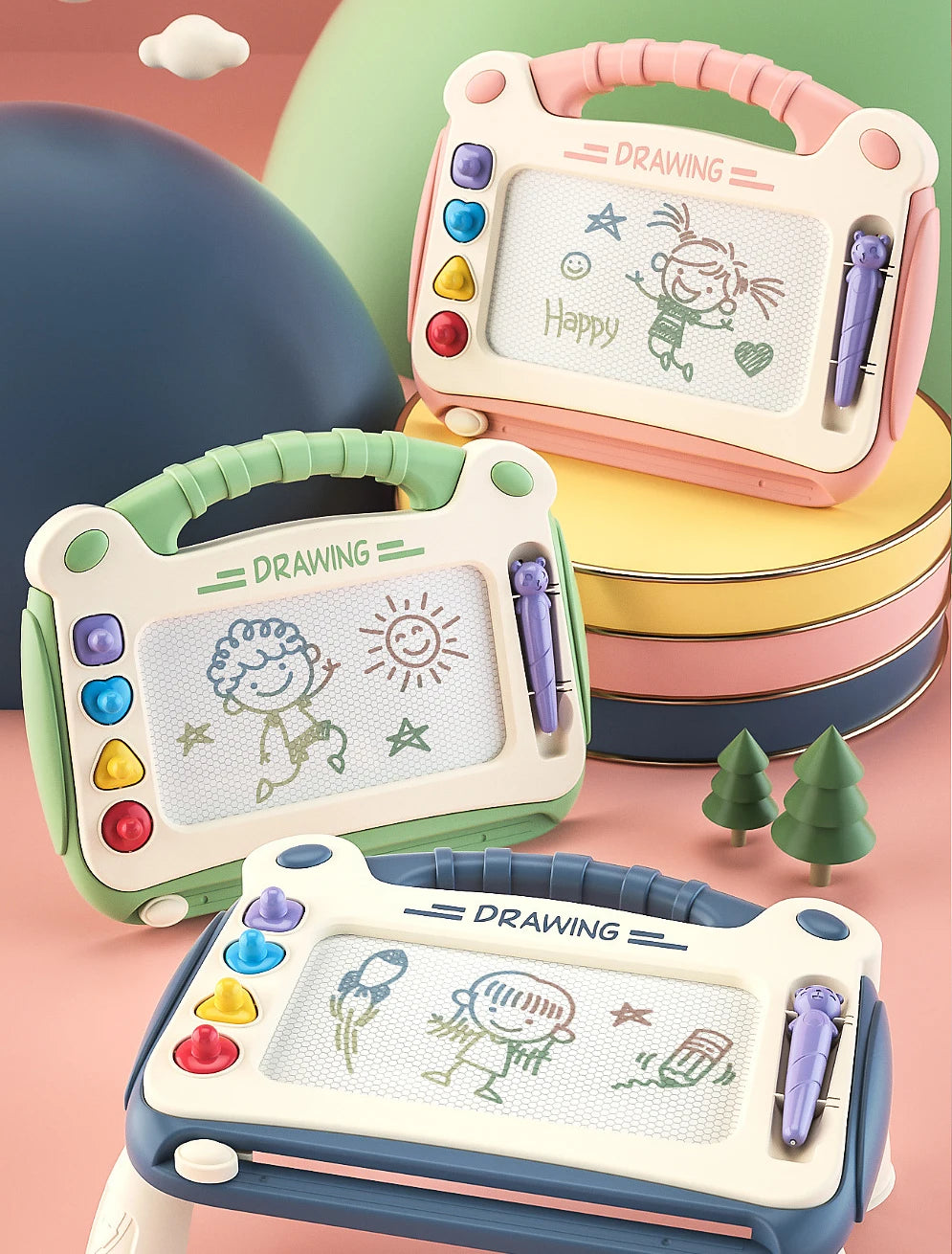 A set of three magnetic drawing boards for kids with erasable pens stacked on a pink surface.