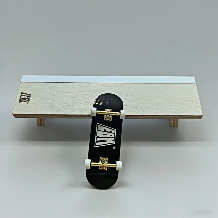 A black fingerboard skateboard is displayed on a light wooden ramp set.