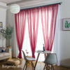 A set of sheer red curtains with a rod pocket filtering light in a bright room.