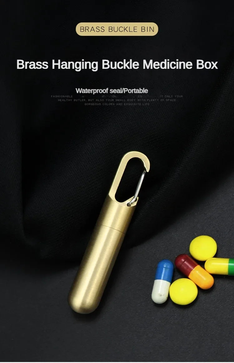 A brass hanging buckle medicine box with a keychain is shown next to several yellow and red pills.