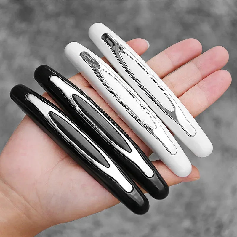 A hand holds four black and white car door edge protector strips.
