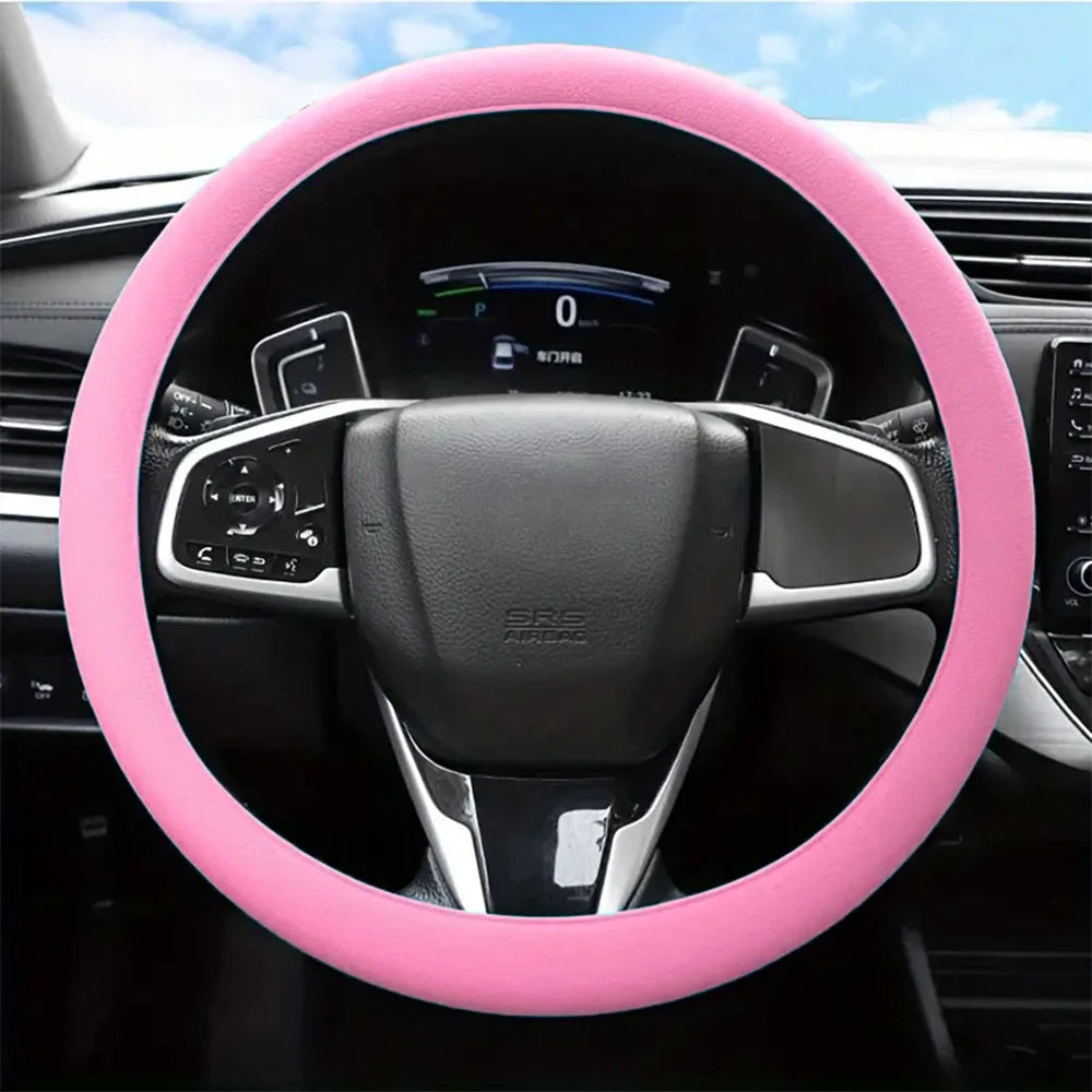 A pink silicone steering wheel cover is shown inside a car, featuring an airbag and controls.