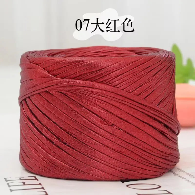 A spool of deep red metallic flat ribbon yarn for crochet and knitting.