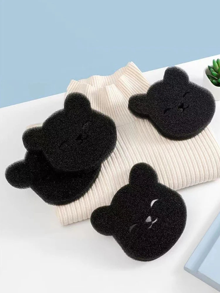Un ensemble de trois tampons en feutre noir pour retirer les poils d'animaux, posés sur un tissu beige clair.