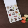 A white sticker book featuring various fruit, shoe, and accessory illustrations on a brown background.