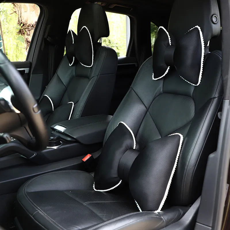 Black car seat interior showing a silky bow headrest pillow and waist cushion set.