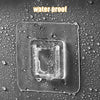 Clear plastic adhesive hooks placed on a water-proof surface covered in water droplets.