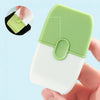 A double-ended cleaning scraper with a protective green cover and white blade is held in a hand.