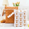 A pair of orange and white patterned mini waterproof wet dry bags for baby resting on a white surface.