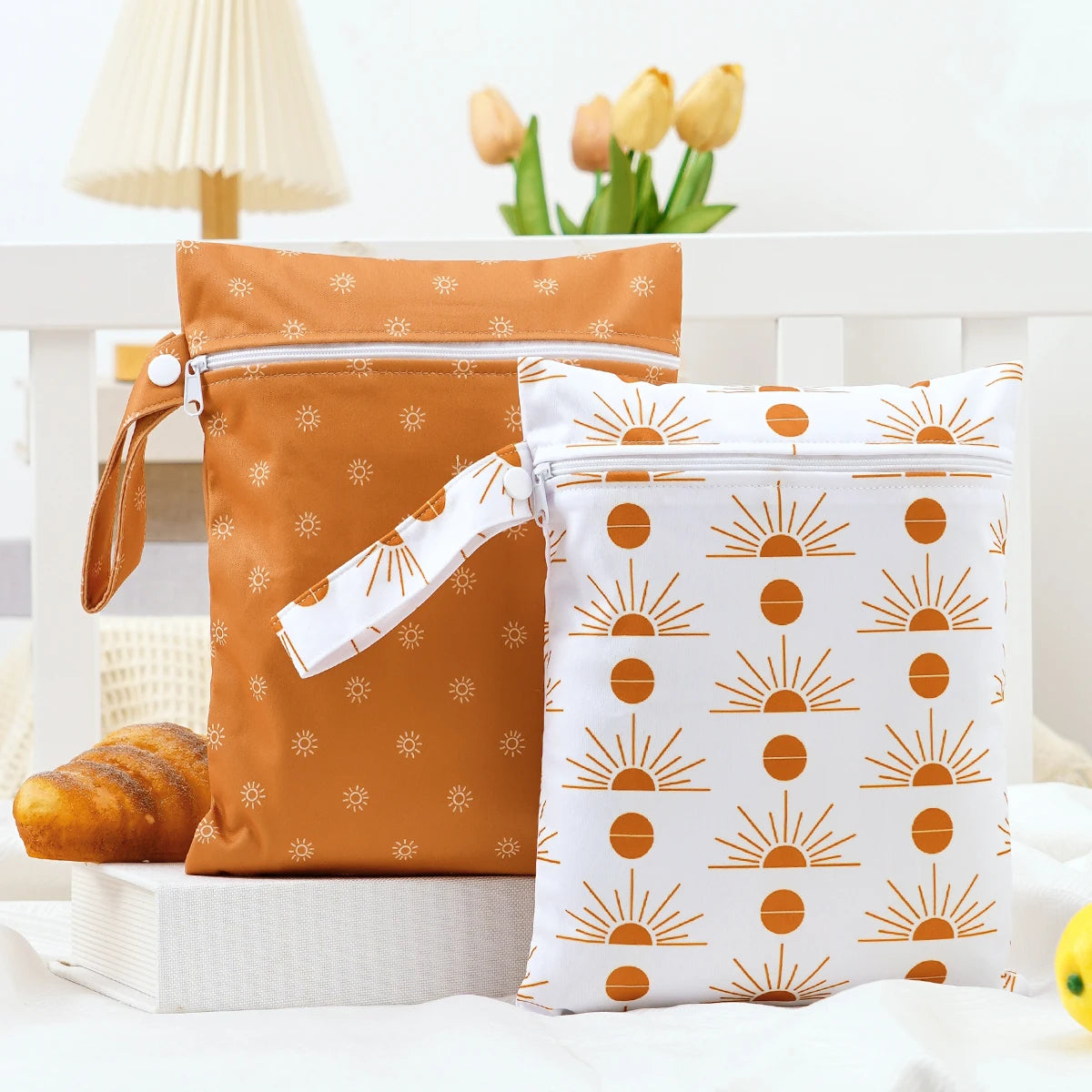 A pair of orange and white patterned mini waterproof wet dry bags for baby resting on a white surface.