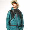 A person wearing a teal waterproof tactical waist bag and a straw hat looking forward.